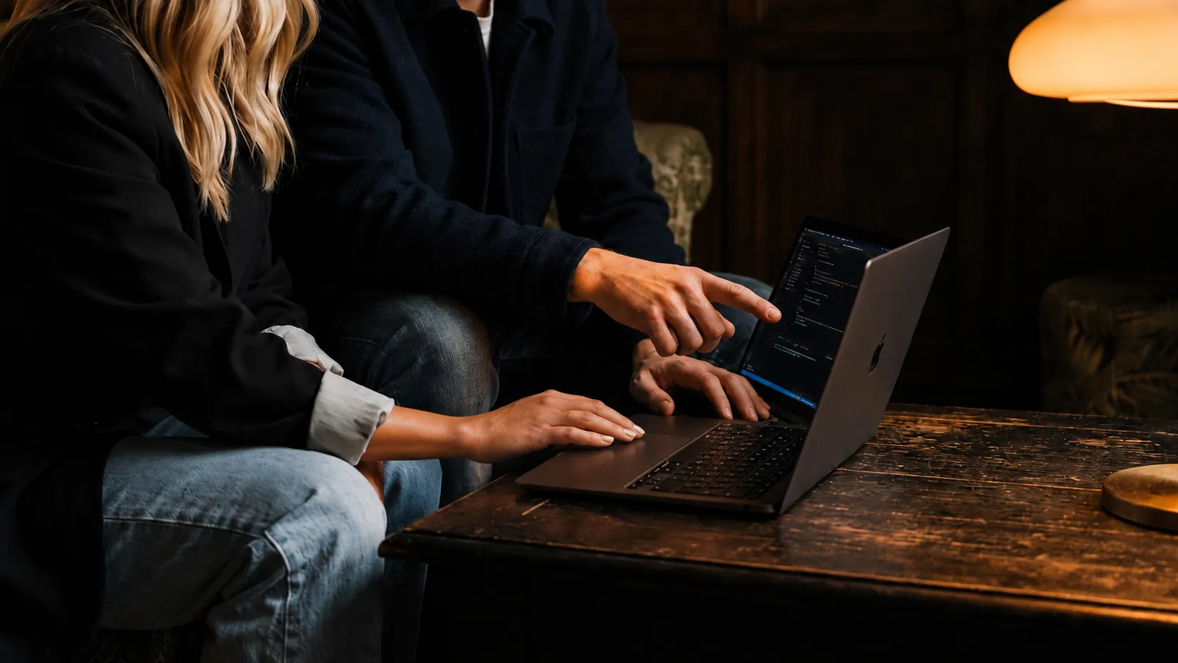 Twee mensen samen achter een laptop op een houten tafel